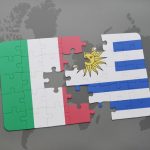puzzle with the national flag of italy and uruguay on a world map background.
